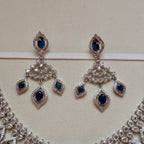 Pair of silver earrings with blue gemstones on a beige background