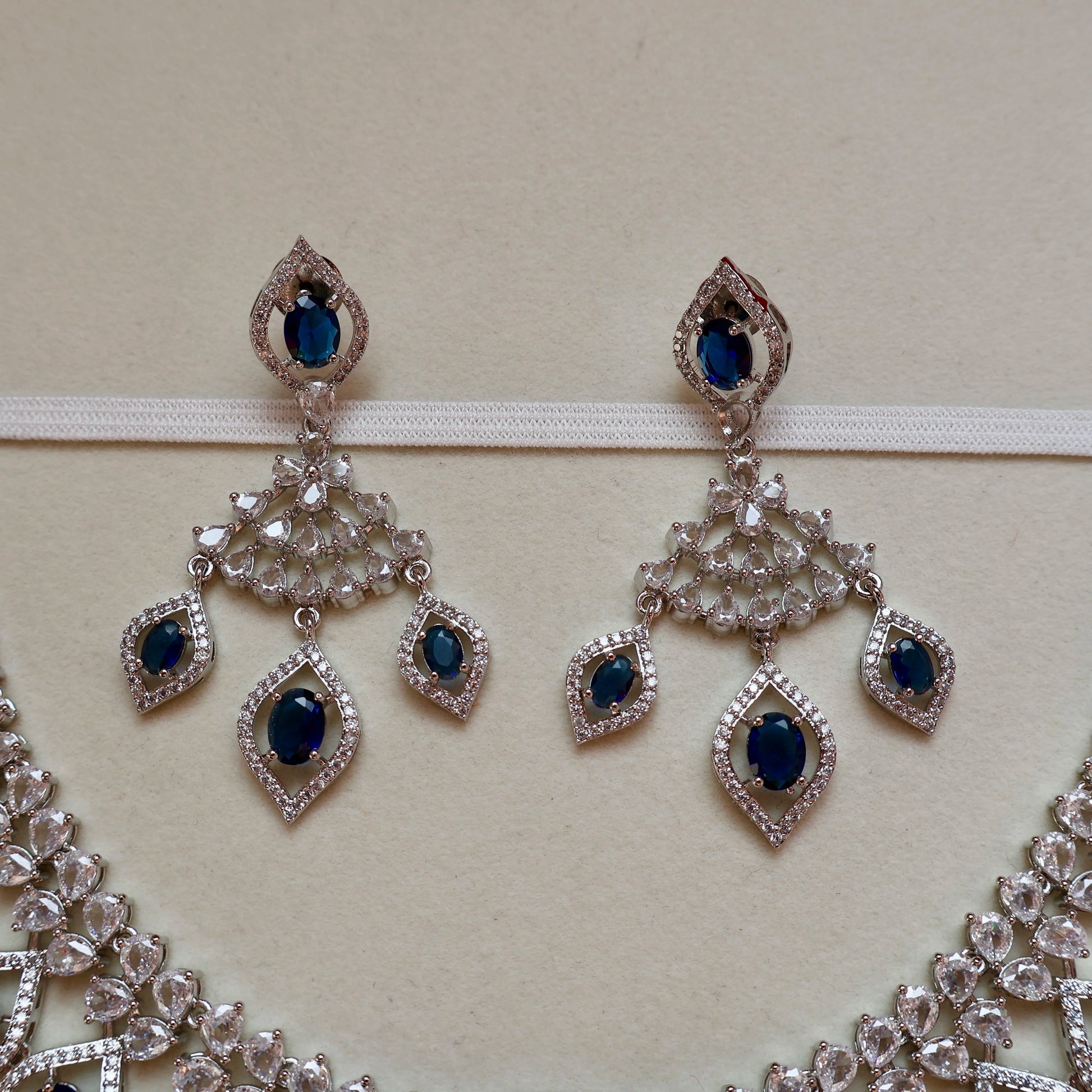 Pair of silver earrings with blue gemstones on a beige background