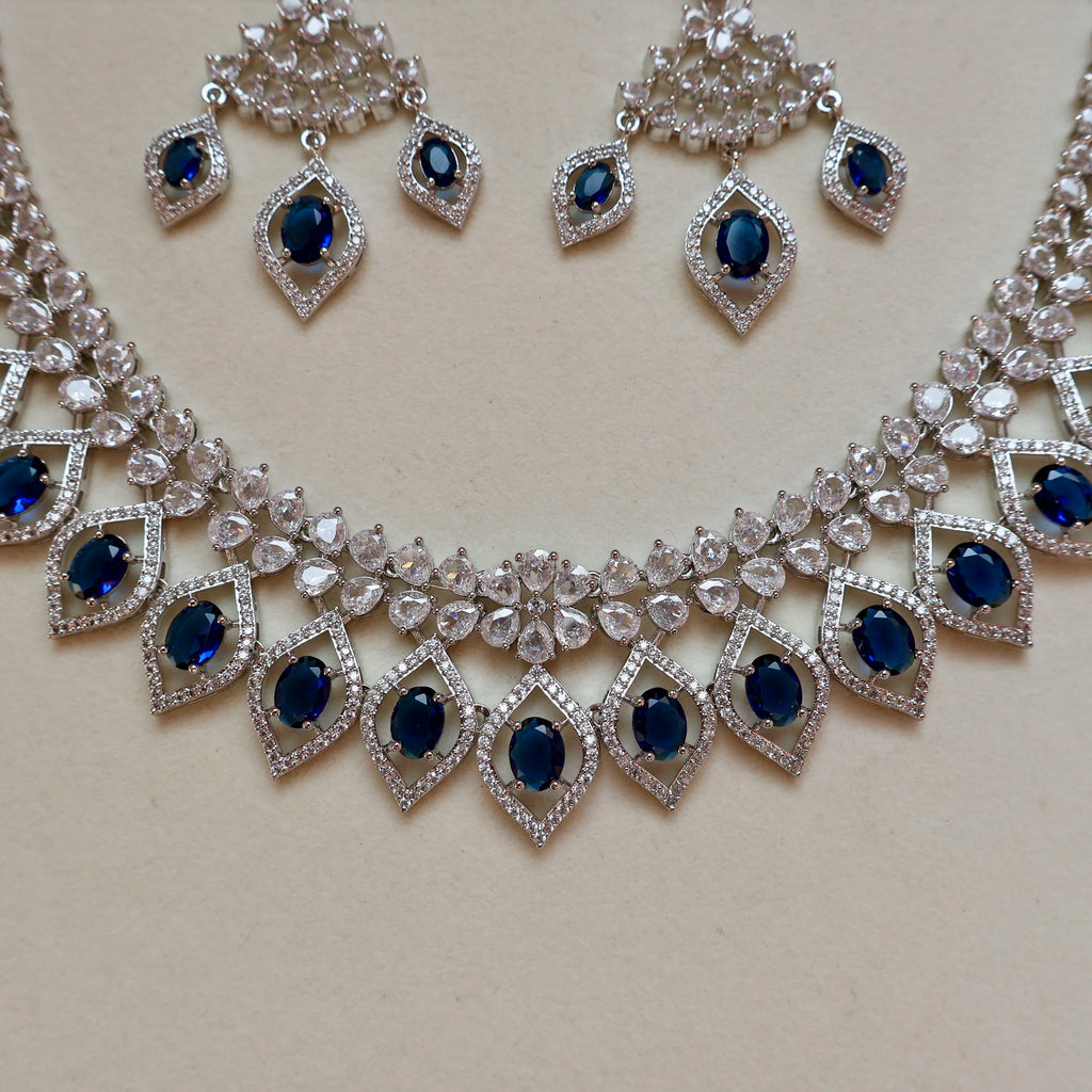 Silver necklace with blue stones and matching earrings on a light background