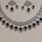 Silver necklace with blue stones and matching earrings on a light background