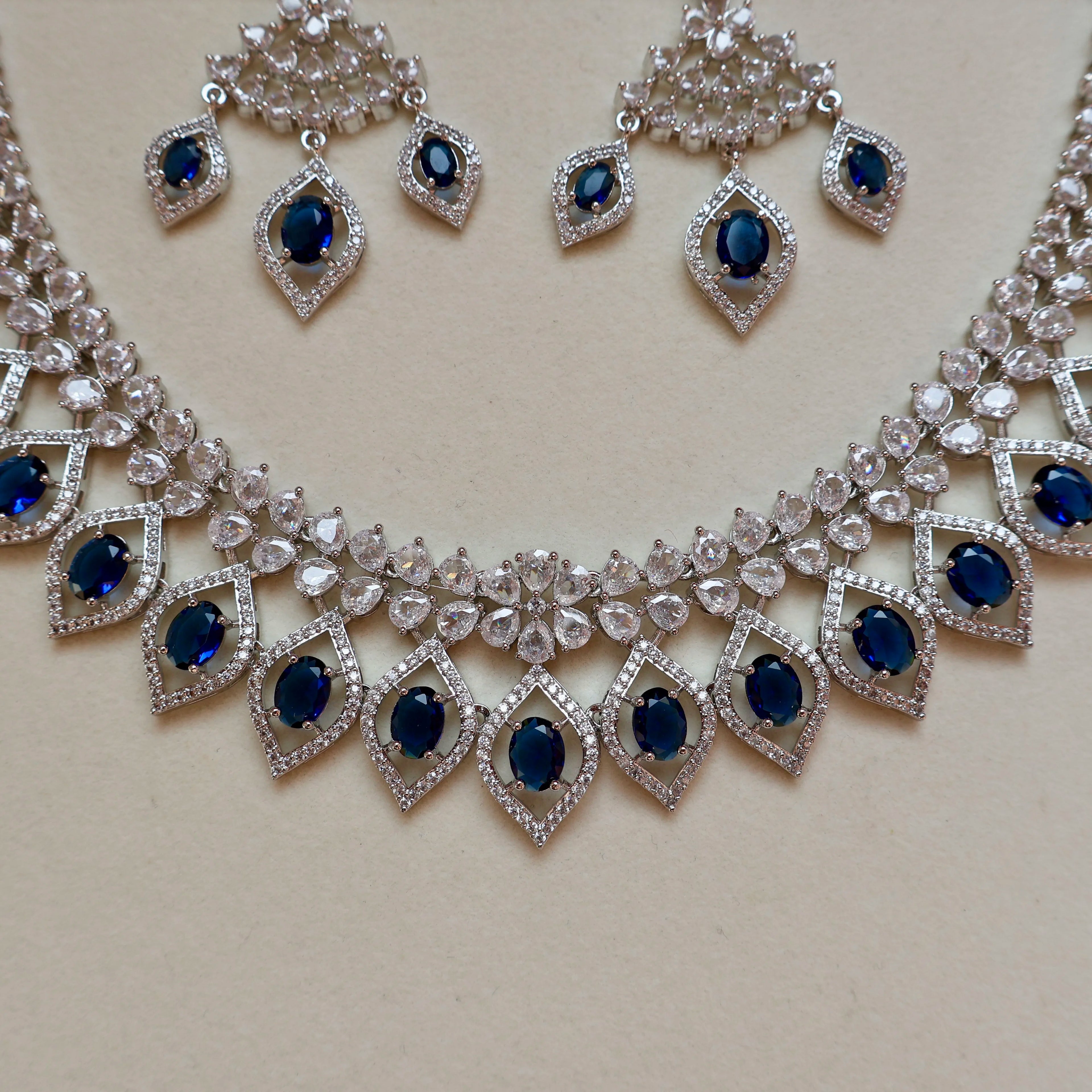 Silver necklace with blue stones and matching earrings on a light background