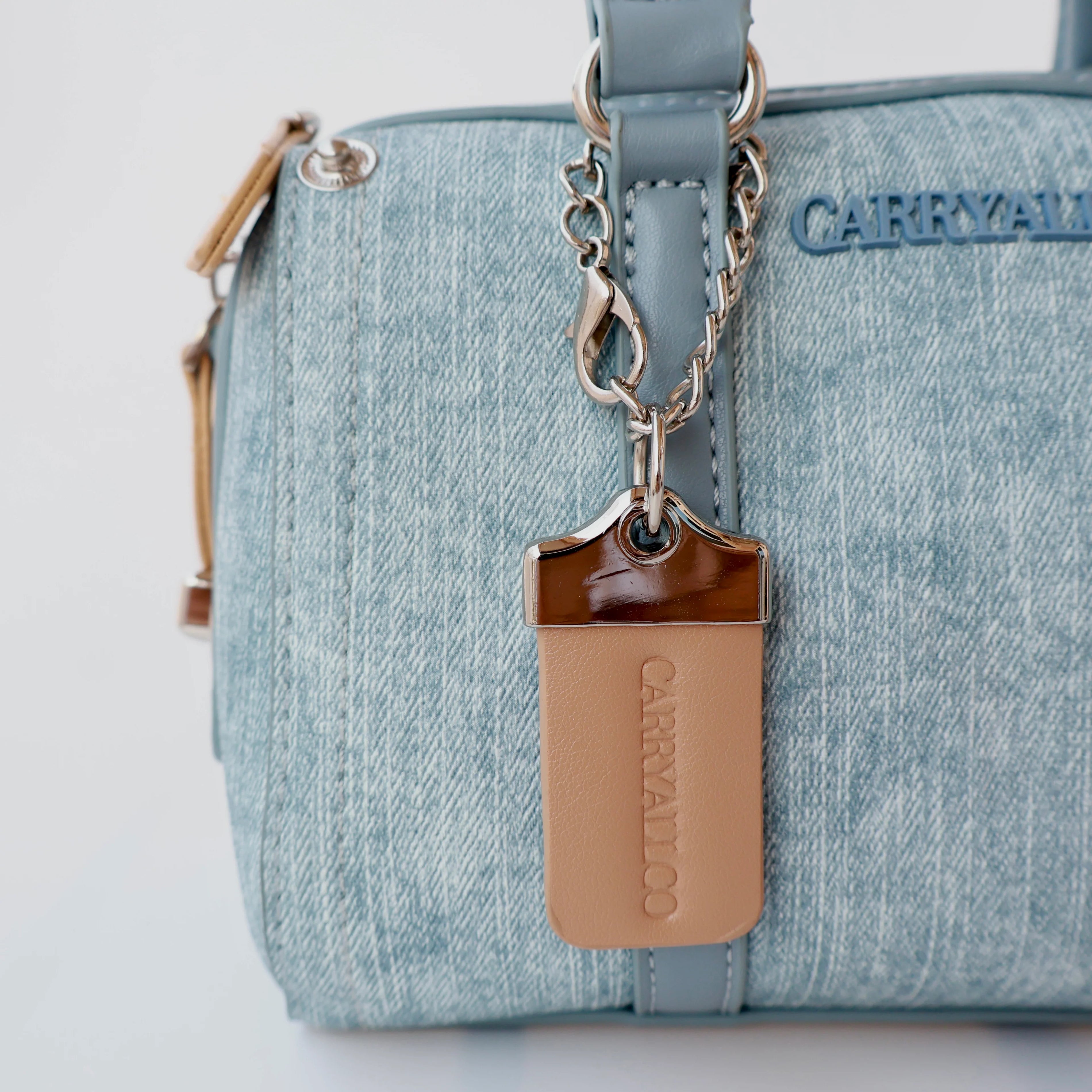 Light blue handbag with a brown tag and 'CARRIVAN' branding on a light gray background
