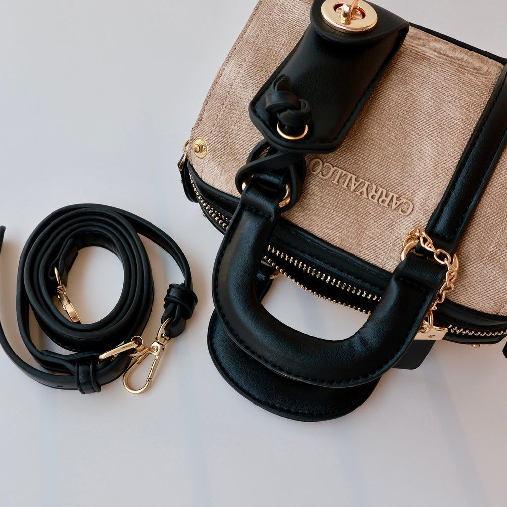 Designer handbag with beige leather and black handles on a light gray background