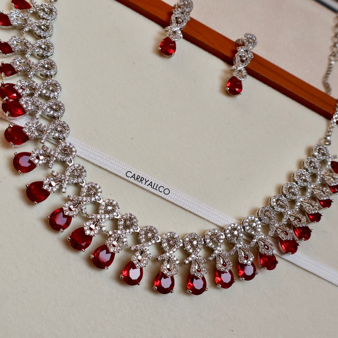 Necklace with red gemstones and silver accents on a white stand with 'CARRYALCO' branding.