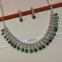Jewelry set with necklace and earrings on a white background, featuring green gemstones and silver accents.
