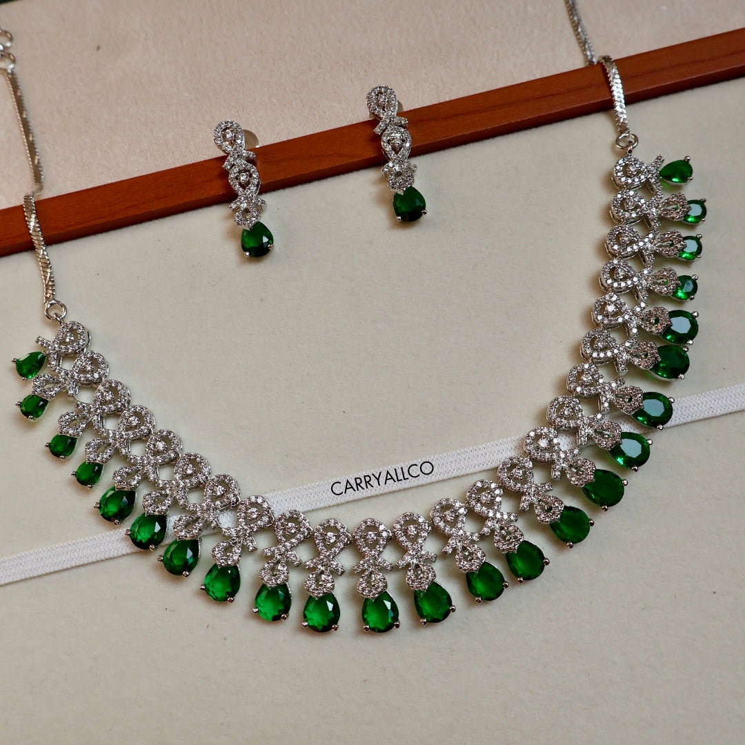 Jewelry set with necklace and earrings on a white background, featuring green gemstones and silver accents.