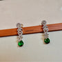 Pair of green gemstone earrings on a wooden stick with 'CARRYALICO' branding.