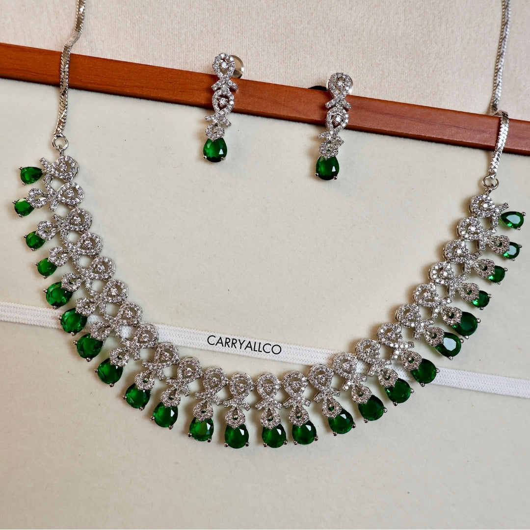 Necklace and earrings with green gemstones on a white background