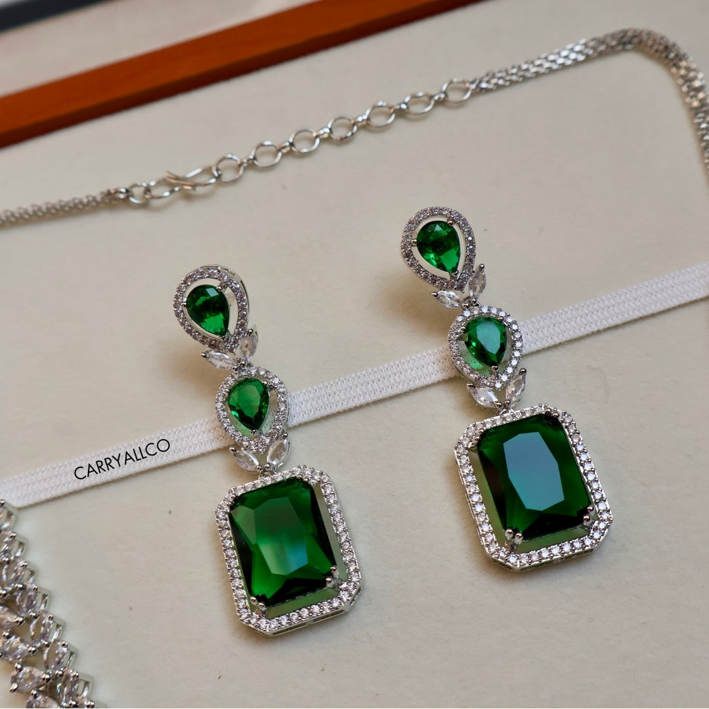 Green gemstone earrings with silver accents on a white ribbon, branded 'CARRYALCO'.