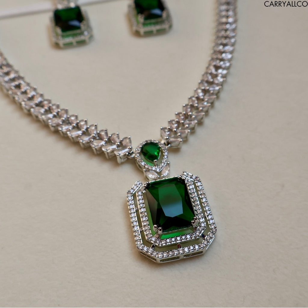 Necklace with green gemstone pendant and matching earrings on a light background