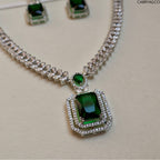 Necklace with green gemstone pendant and matching earrings on a light background