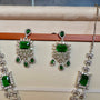 Jewelry set with green gemstones on a beige surface