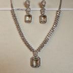 Silver necklace and earrings with gemstones on a beige background