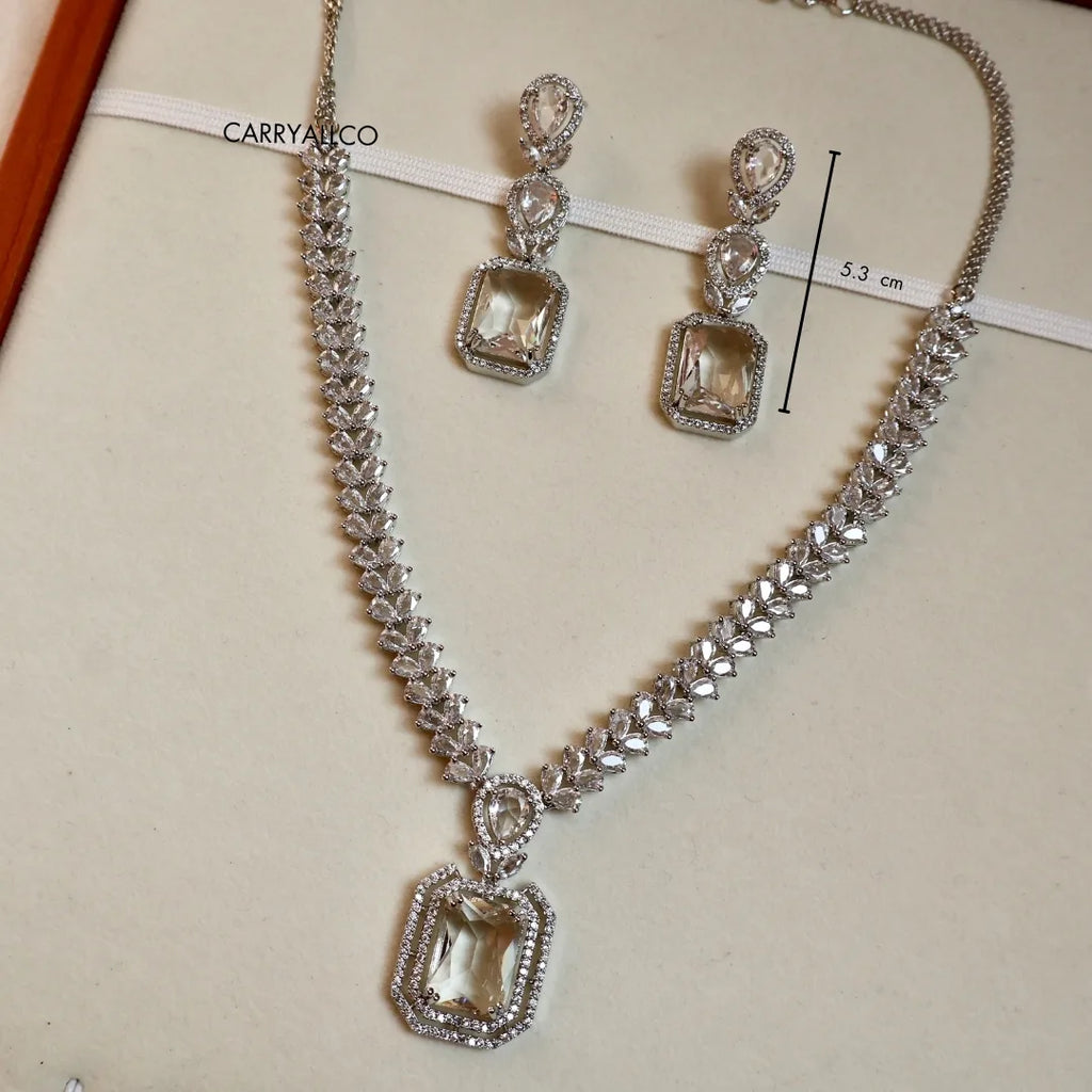 Silver necklace and earrings with gemstones on a beige background