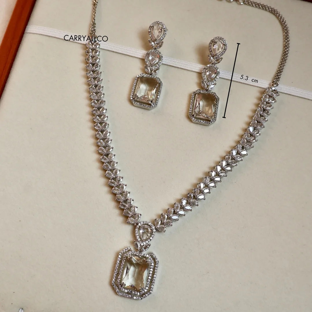 Silver necklace and earrings with gemstones on a beige background