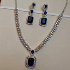 Jewelry set with necklace and earrings featuring blue gemstones on a beige background