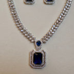 Jewelry set with necklace and earrings featuring blue gemstones on a light background