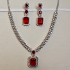 Jewelry set with necklace and earrings featuring red gemstones on a light background