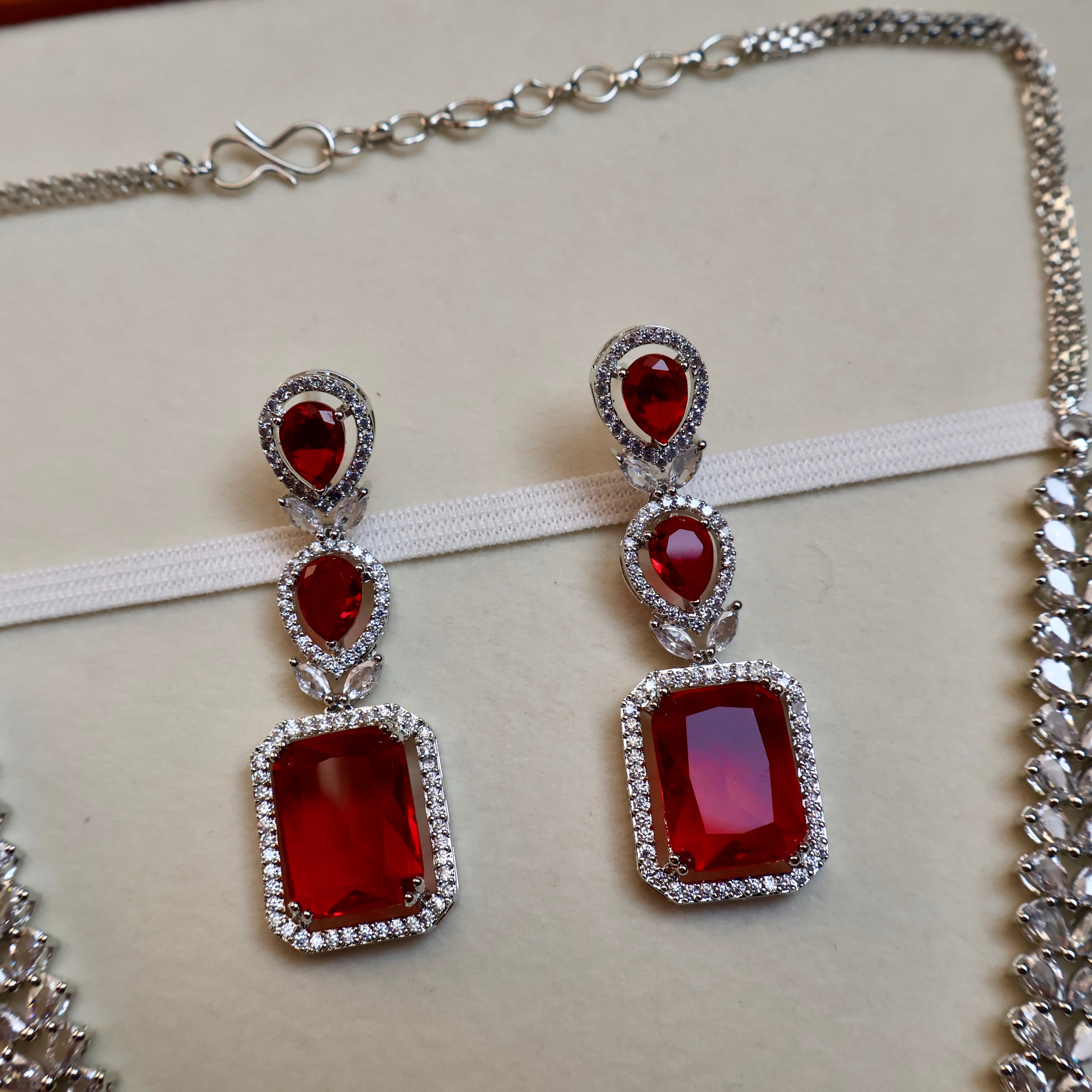 Red gemstone earrings with silver frames on a white background