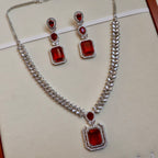 Jewelry set with necklace and earrings featuring red gemstones on a light background
