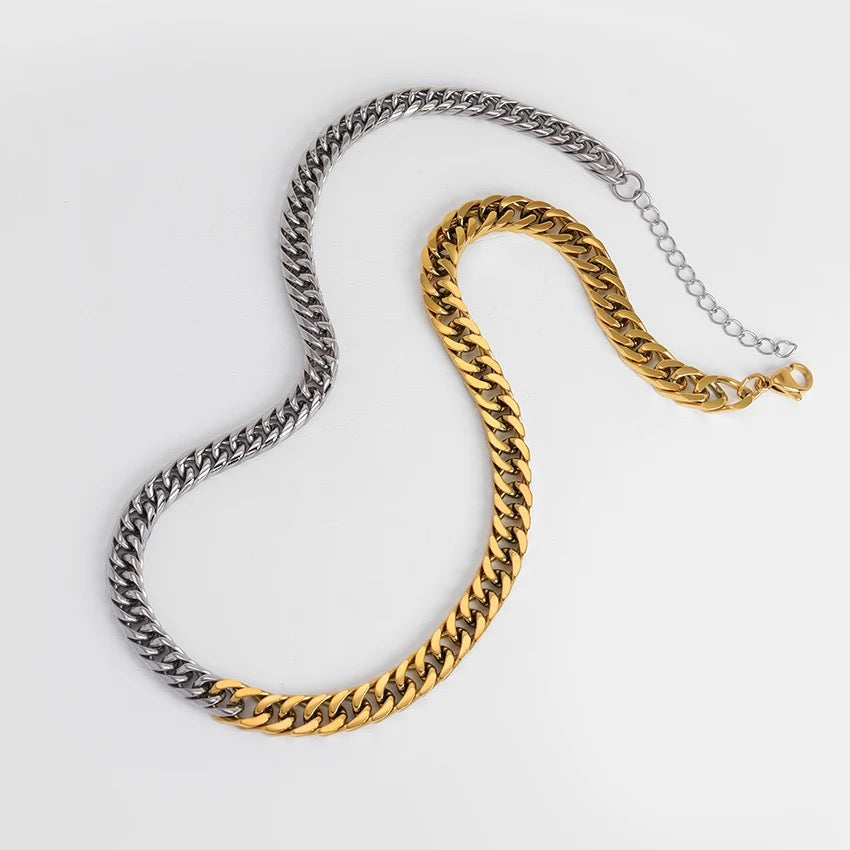 Two chain necklaces, one gold and one silver, on a light gray background.