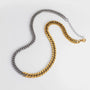 Two chain necklaces, one gold and one silver, on a light gray background.