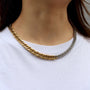 Gold chain necklace worn by a person on a white background