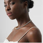 Woman wearing a delicate necklace with a plain background