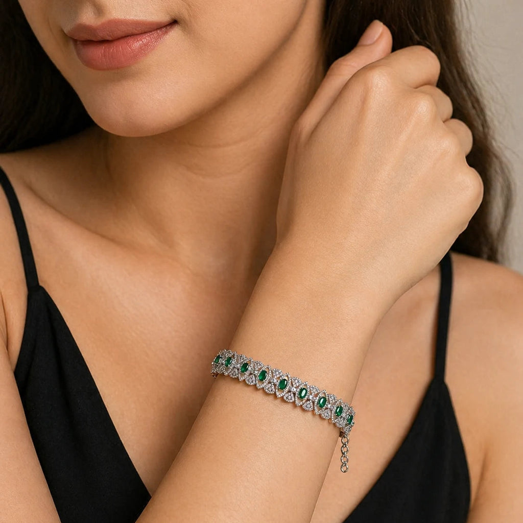 Close-up of a woman wearing a bracelet with emerald stones on a neutral background