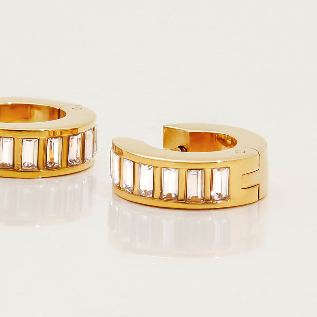 Gold hoop earrings with embedded stones on a light background