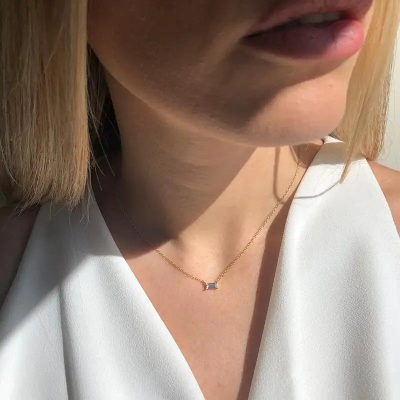 Close-up of a person wearing a delicate necklace with a small pendant.