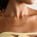 Gold necklace with small diamonds on a model wearing a yellow top.