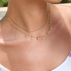 Gold necklace with small pendants on a person's neck