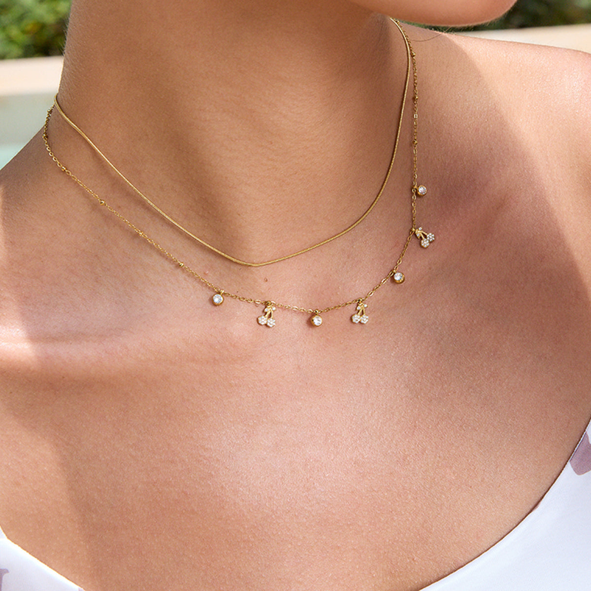 Gold necklace with small pendants on a person's neck