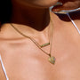 Close-up of a person wearing two gold necklaces with heart pendants.