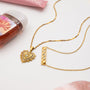 Gold necklaces with heart and rectangular pendants on a white surface.