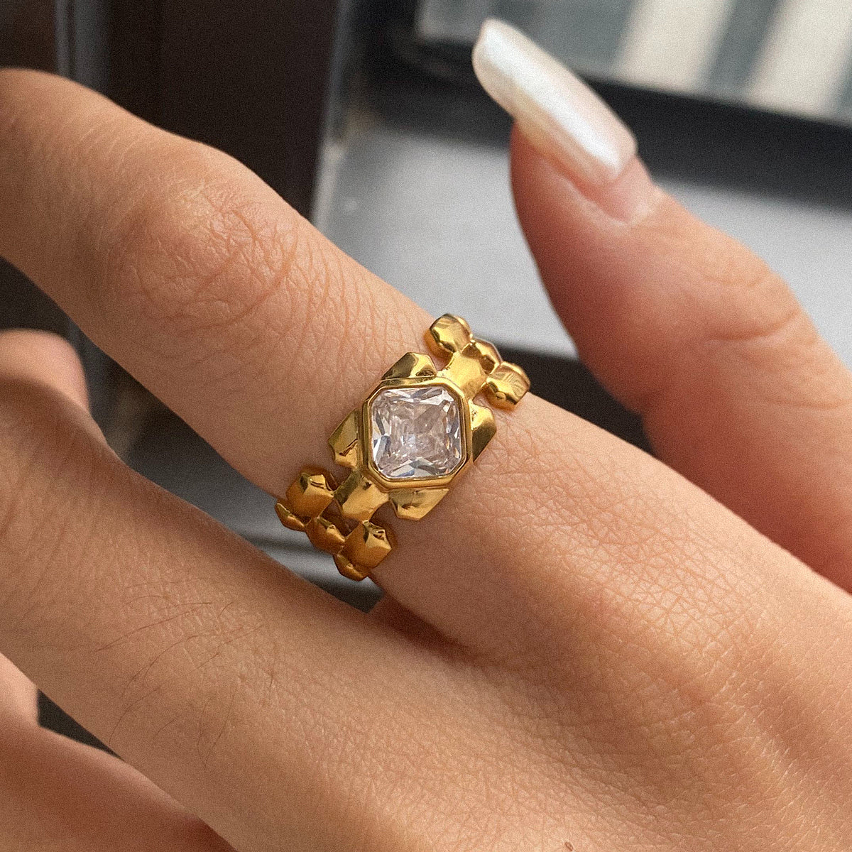 Gold ring with a diamond on a finger against a blurred background