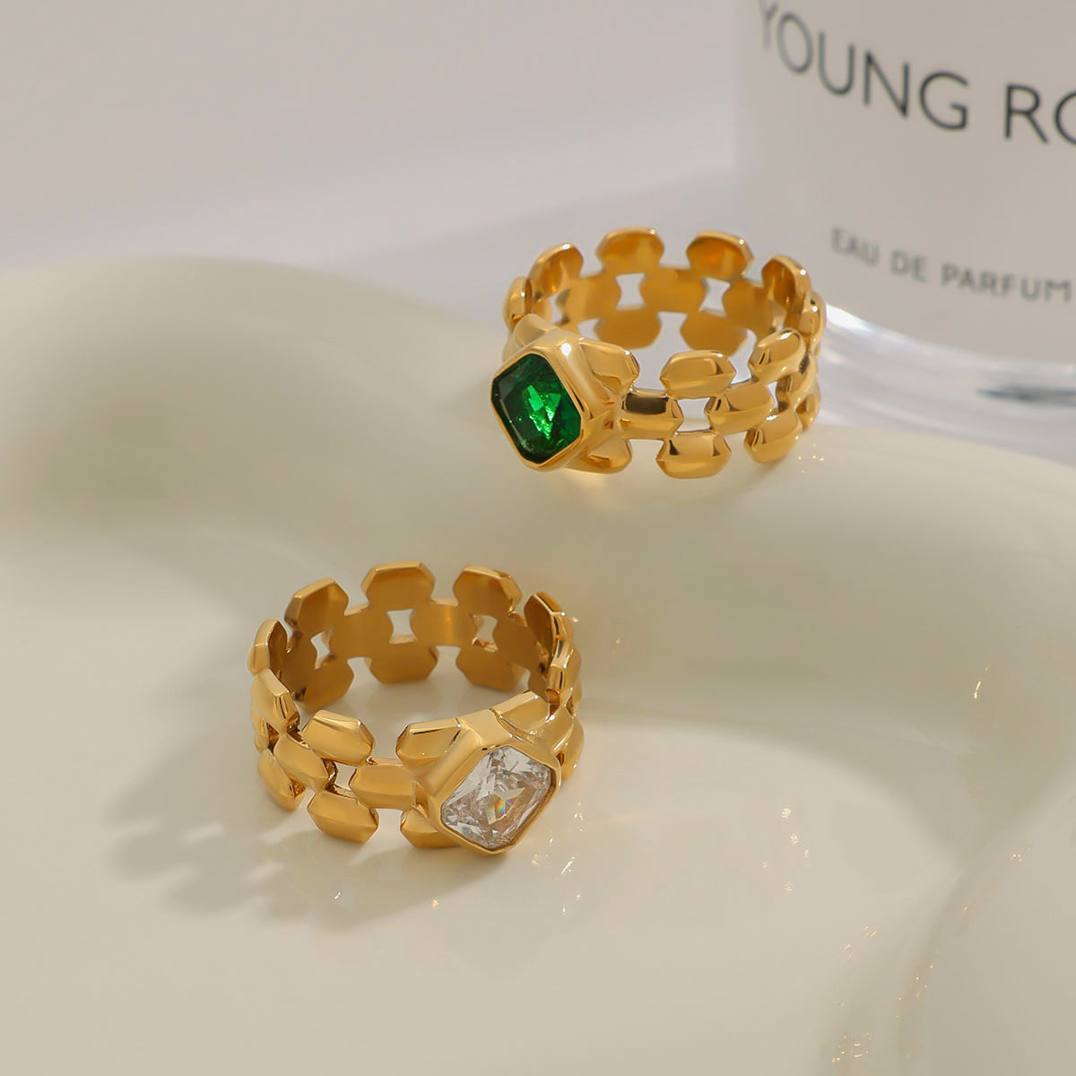 Two gold rings with gemstones on a white surface