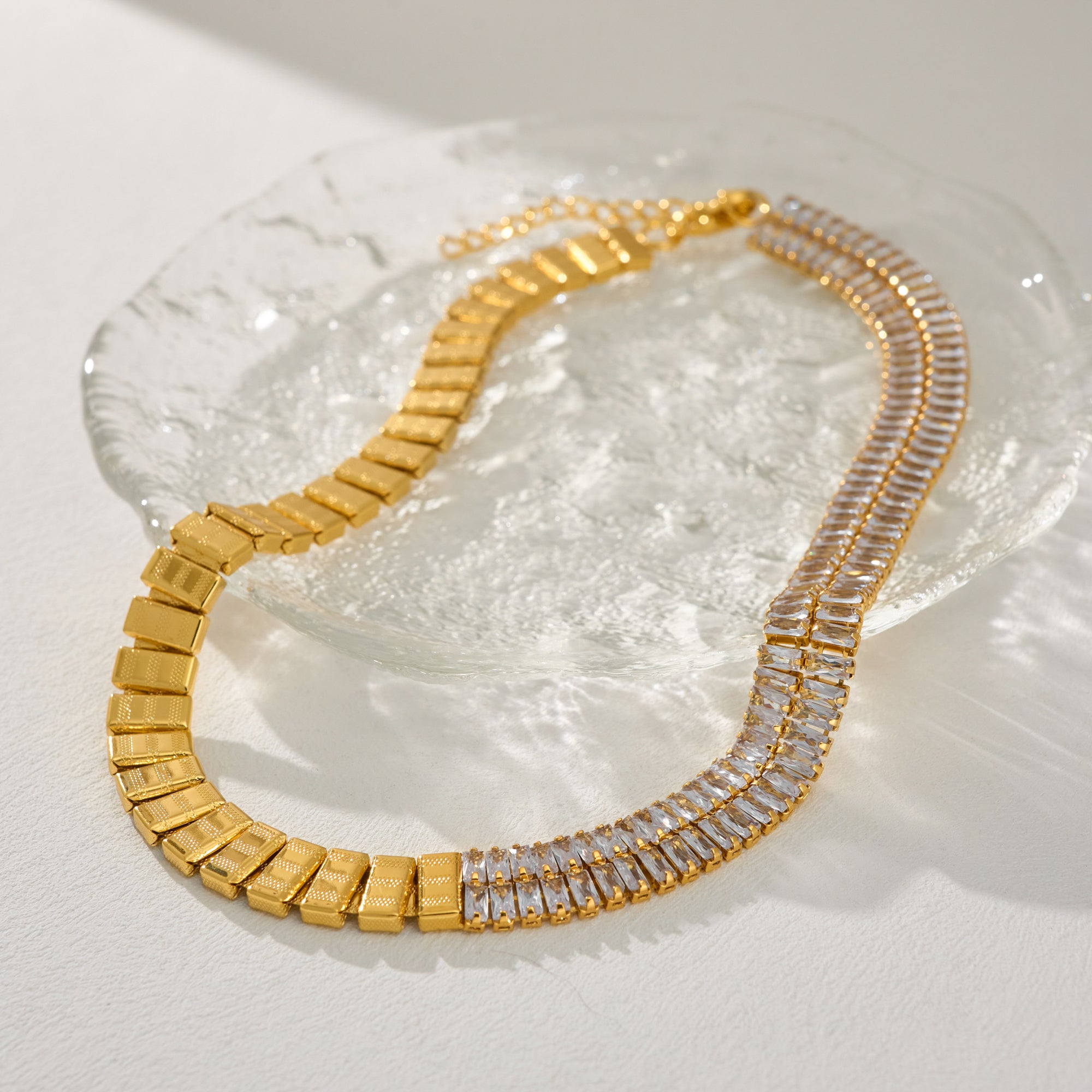 Gold necklace with clear stones on a textured white surface
