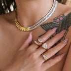 Close-up of a person wearing a gold necklace and multiple rings on a blurred background
