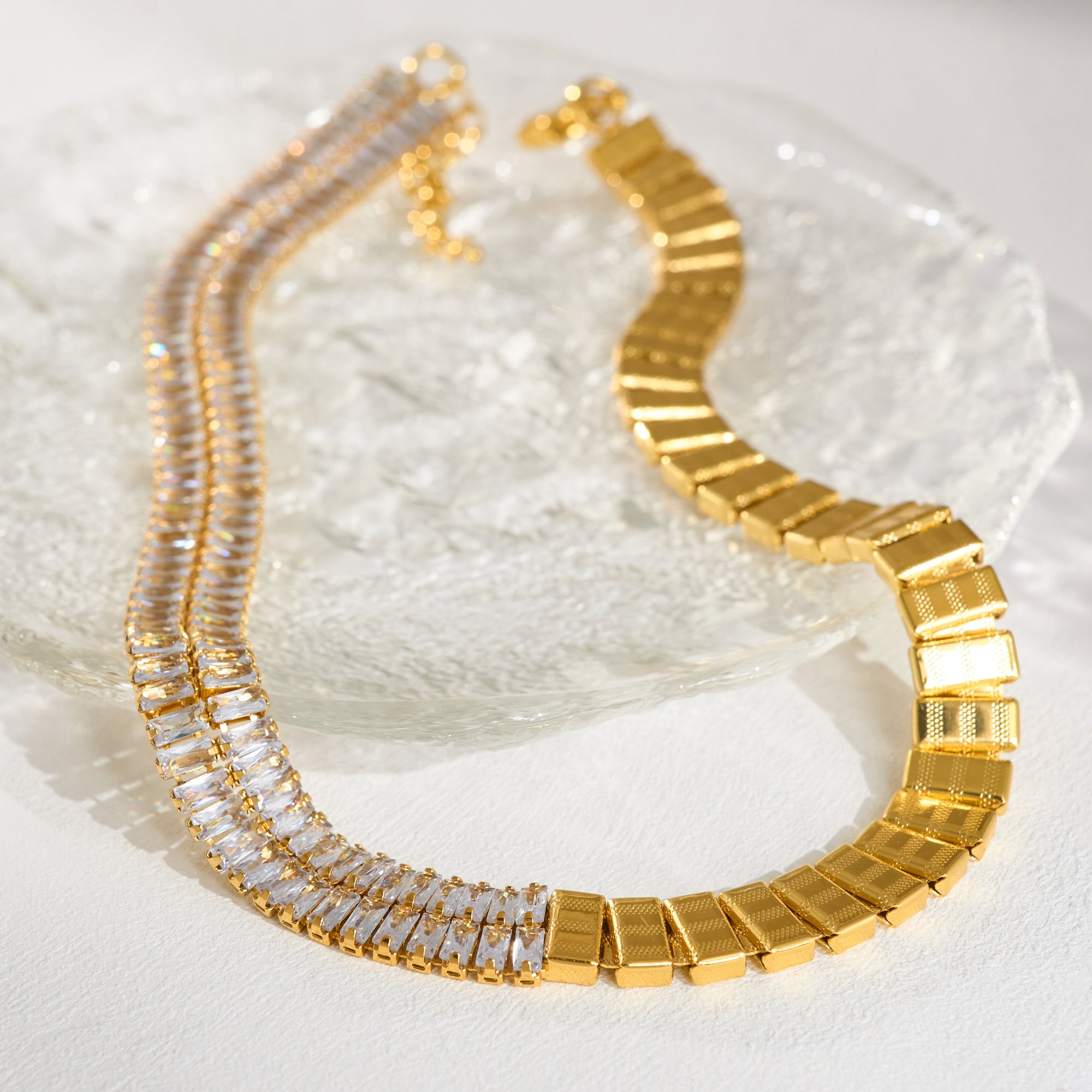 Gold necklace with clear stones on a textured white surface