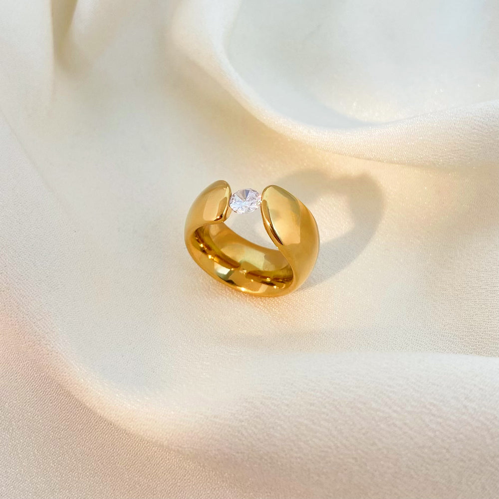 Gold ring with a diamond on a soft beige background