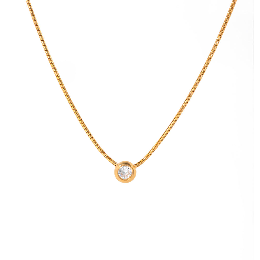 Gold necklace with a small round pendant on a white background