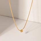 Gold necklace with a round pendant on a light beige background