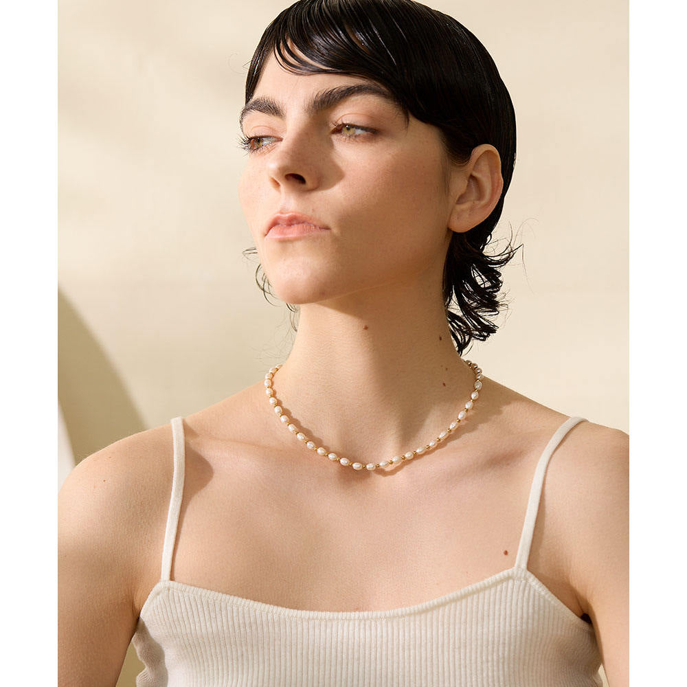 Woman wearing a pearl necklace against a beige background
