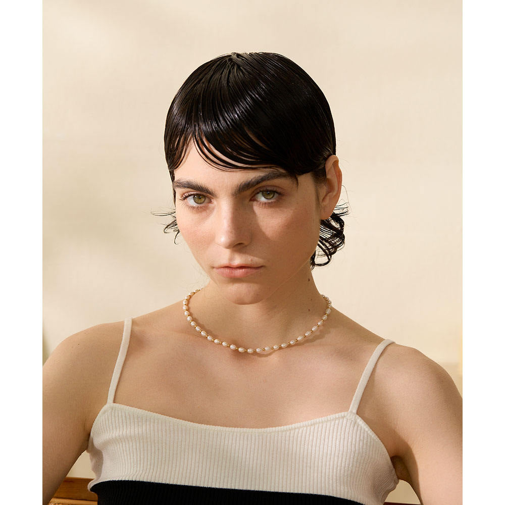 Woman wearing a pearl necklace against a beige background