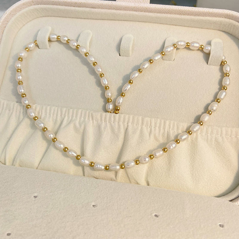 Pearl and gold necklace on a beige jewelry box with sand in the background