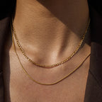 Gold chain necklace on a person's neck with a dark background