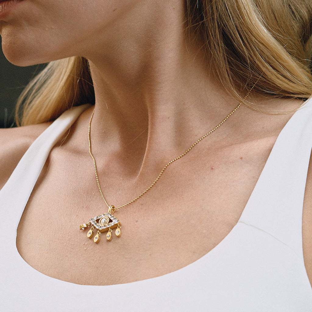 Gold necklace with a pendant on a person wearing a white top