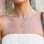 Gold necklace with a pendant worn by a person in a white top.